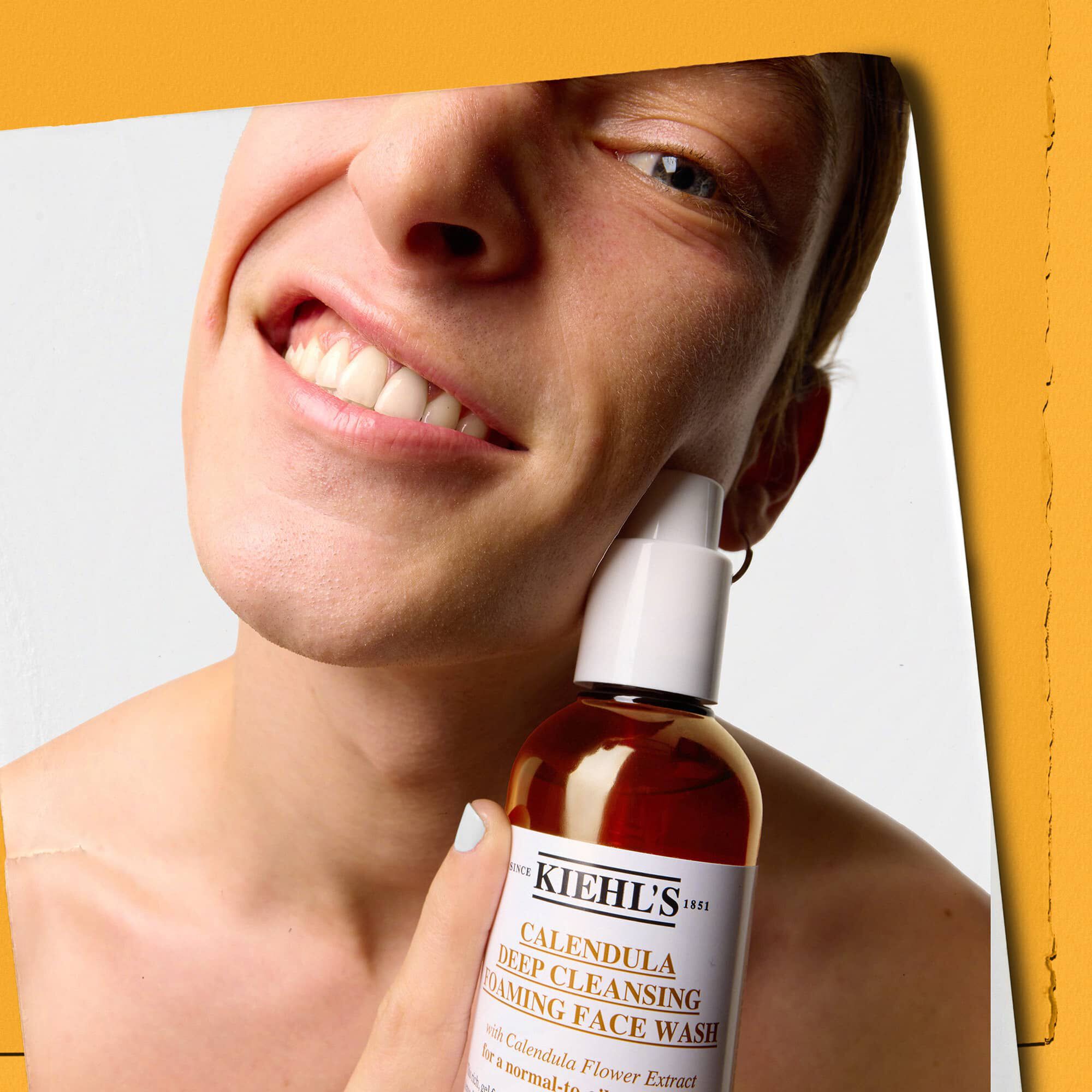 Modella con in mano un flacone di detergente Kiehl's Calendula Deep Cleaning Foaming Face Wash
