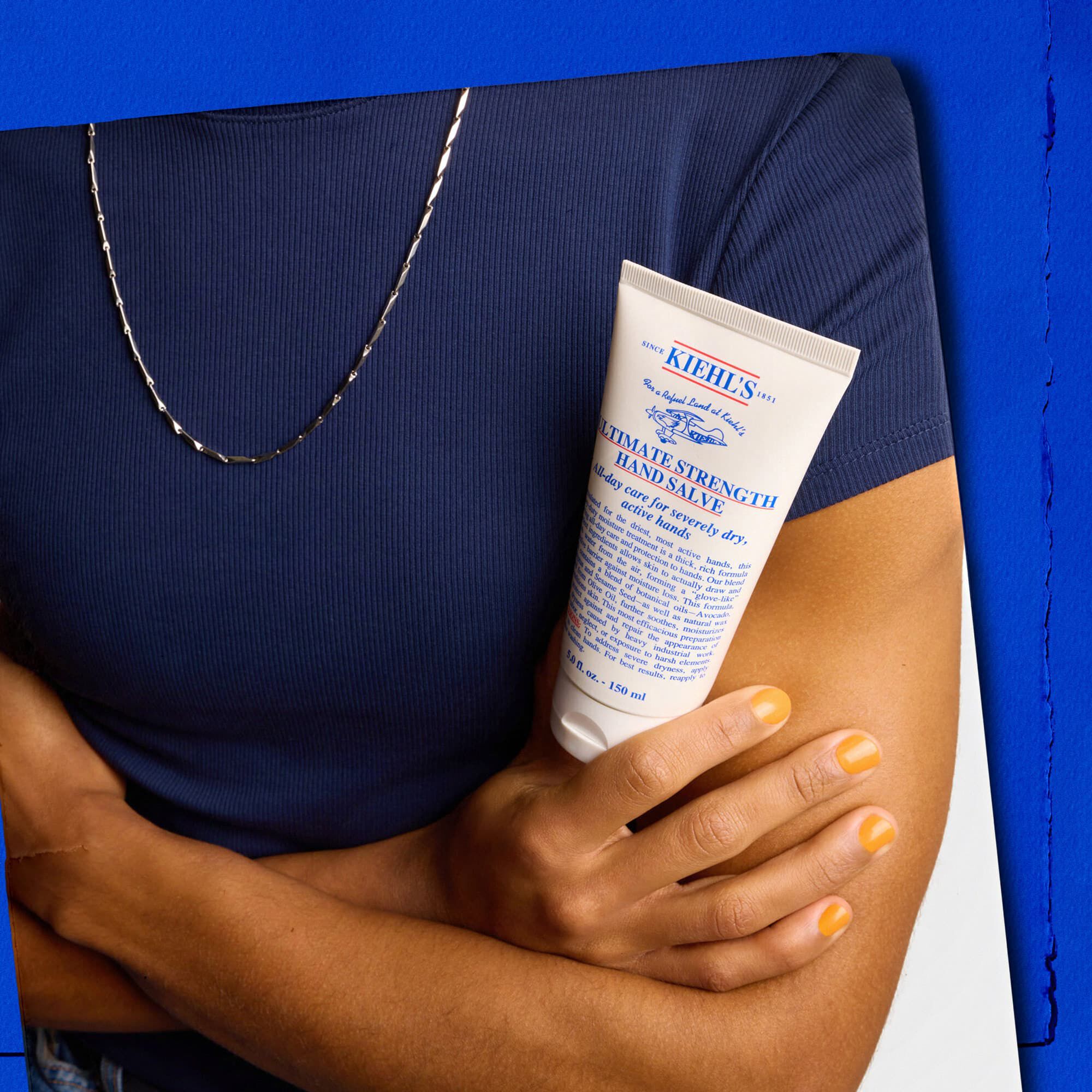 Modella con in mano un tubetto di Kiehl's Ultimate Strength Hand Salve