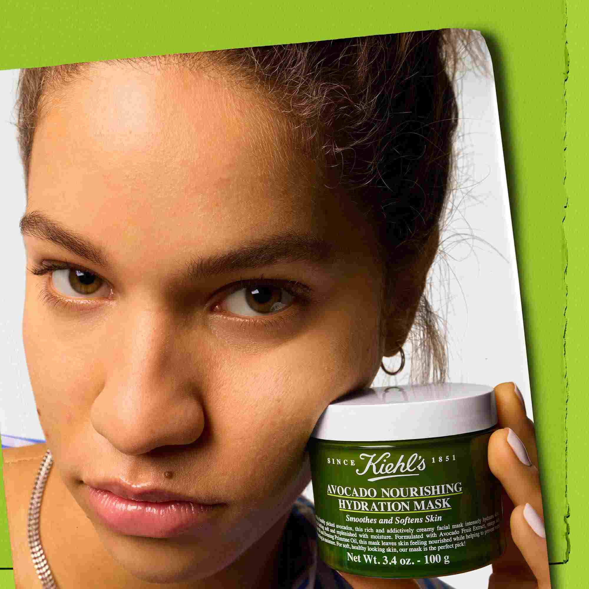 Modella con in mano un vasetto di Kiehl's Avocado Nourishing Hydration Mask: leviga e ammorbidisce la pelle