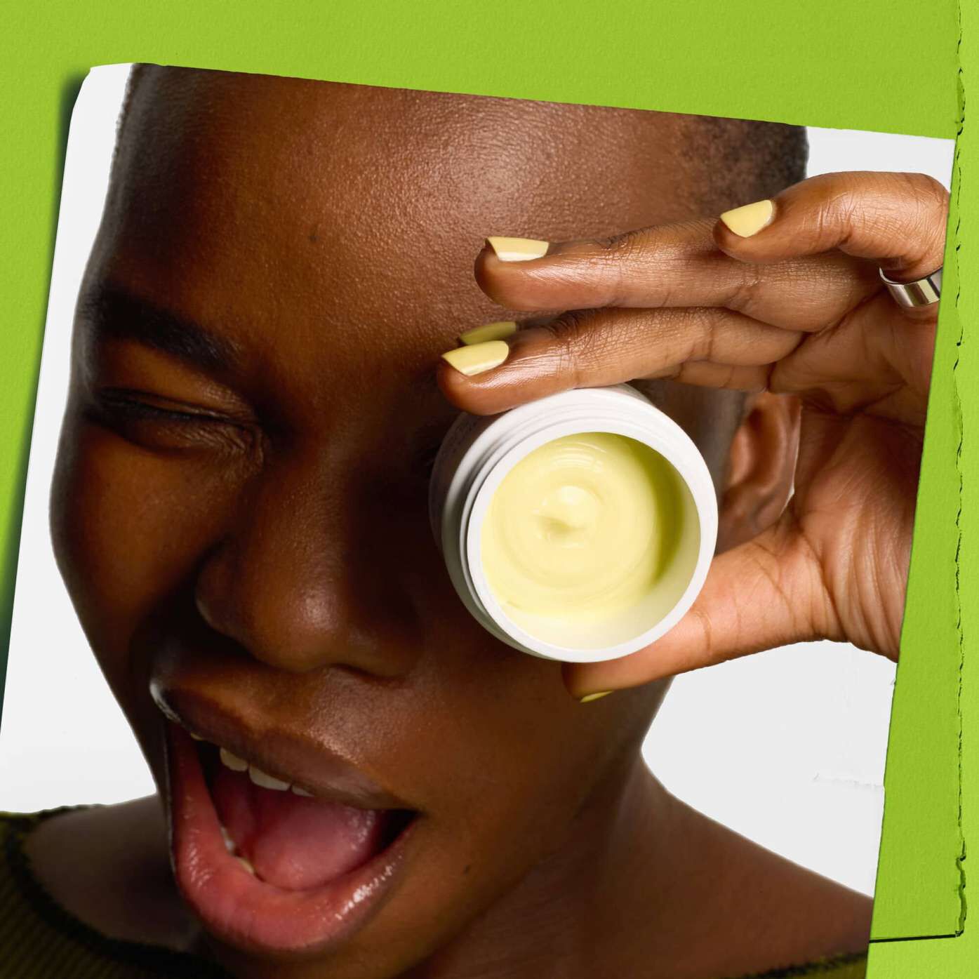 Modella che fa l'occhiolino con un vasetto di Kiehl's Creamy Eye Treatment with Avocado che copre un occhio