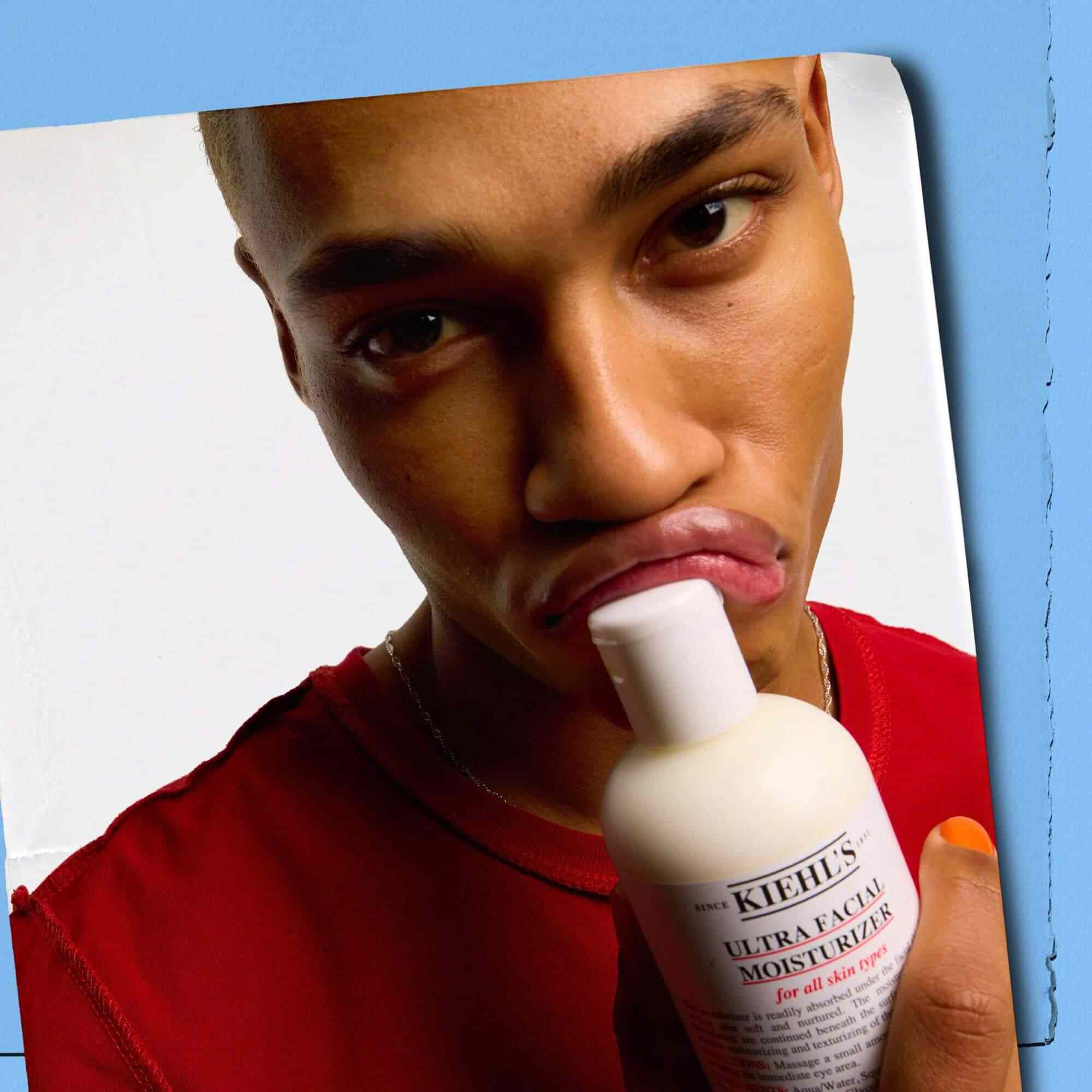 Modella che preme un flacone di Kiehl's Ultra Facial Moisturizer contro le labbra