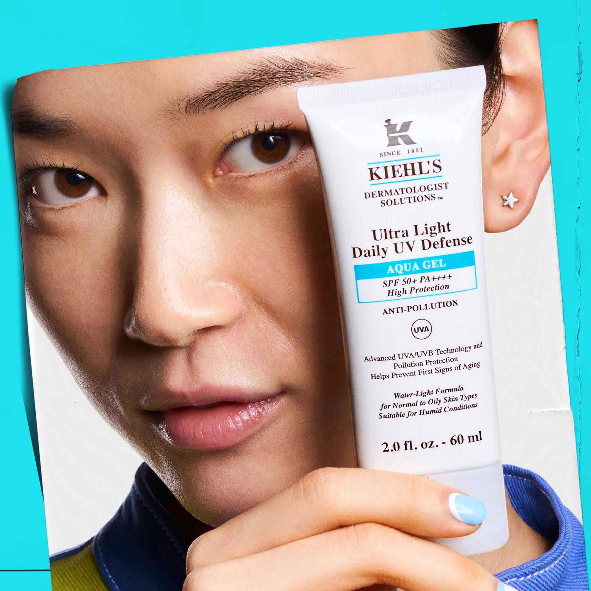 Una modella che tiene un tubetto di Ultra Light Daily UV Defense Aqua Gel, a dimostrazione della sua portabilita e facilita d'uso.