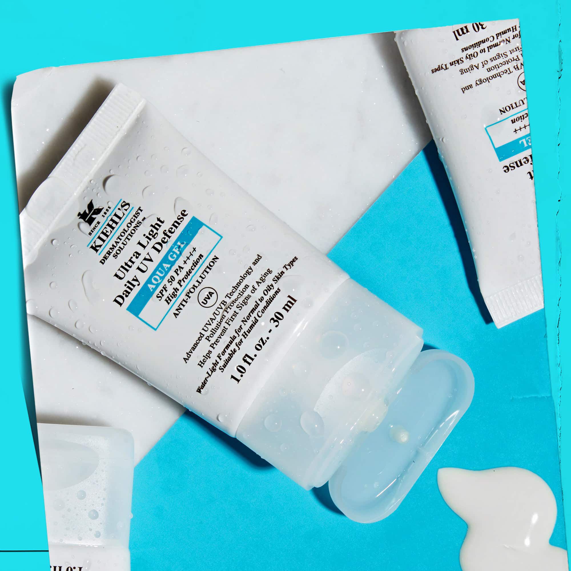 Una composizione flat-lay di piu tubetti di Ultra Light Daily UV Defense Aqua Gel su una superficie di marmo, che ne mostra il fascino lifestyle.