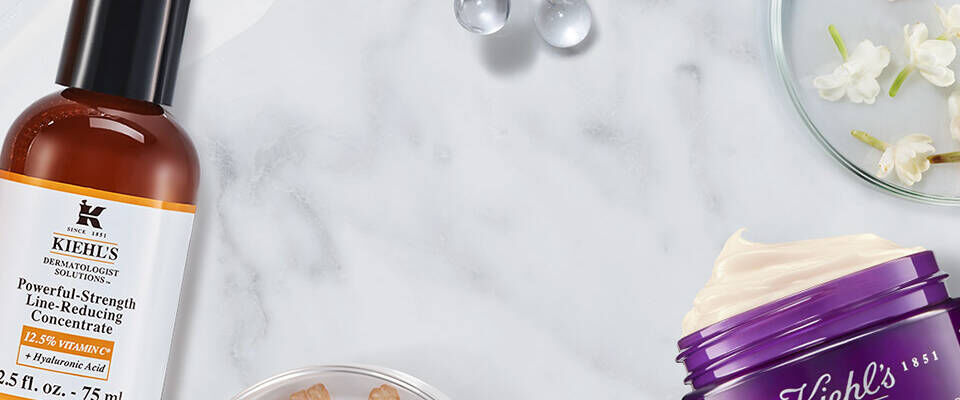 Immagine che mostra una varieta di prodotti per la cura della pelle, tra cui bottiglie e barattoli, disposti su un piano di marmo con decorazioni floreali.